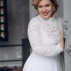 White lace long sleeve bridal blouse paired with satin skirt, classic wedding style.