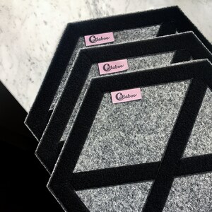 May include: Three gray hexagon-shaped floor mats with black trim and a pink label that says "Catlaboo" on each mat.
