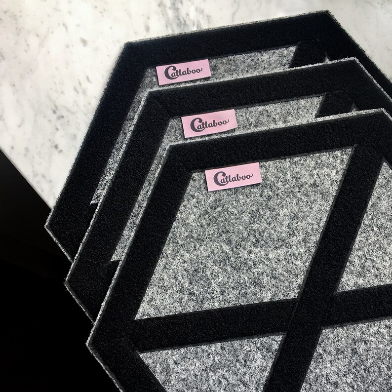 May include: Three gray hexagon-shaped floor mats with black trim and a pink label that says "Catlaboo" on each mat.