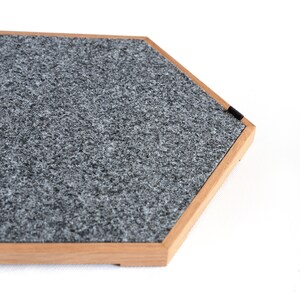 May include: A hexagonal gray felt pad with a wooden frame. The pad is designed to protect surfaces from scratches.