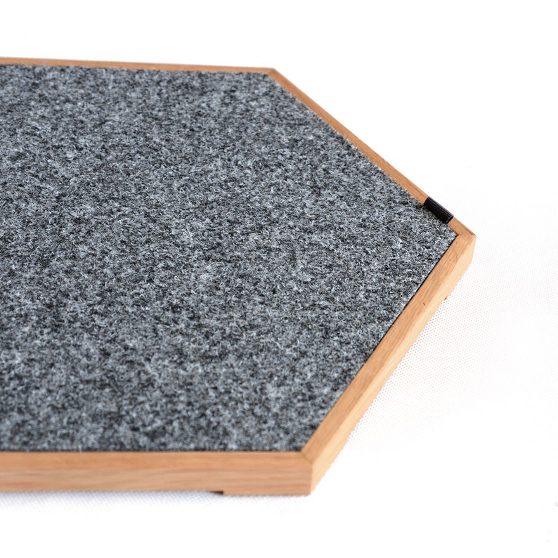 May include: A hexagonal gray felt pad with a wooden frame. The pad is designed to protect surfaces from scratches.
