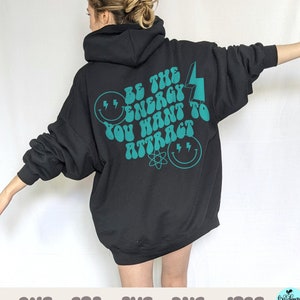 May include: Black hooded sweatshirt with a teal blue graphic print that says "Be the energy you want to attract" with a lightning bolt and smiley faces.