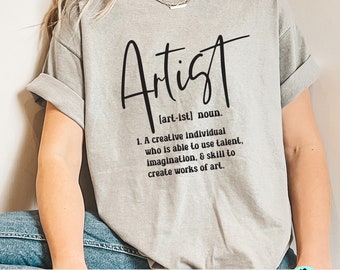 May include: A gray t-shirt with the word "Artist" written in black cursive lettering. The word "Artist" is defined as "[art-ist] noun. 1. A creative individual who is able to use talent, imagination, & skill to create works of art."