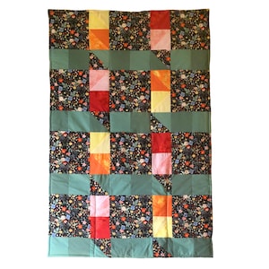May include: A green, red, pink, yellow and orange patchwork quilt with a floral pattern. The quilt is made of squares and triangles.