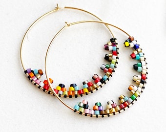 May include: A pair of gold hoop earrings with colourful beaded accents. The beads are arranged in a cascading pattern, creating a vibrant and eye-catching design.
