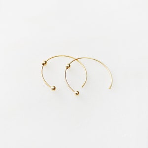 May include: A pair of gold hoop earrings with small ball accents.