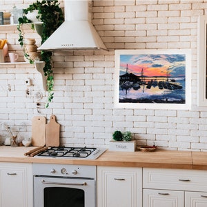 May include: A framed painting of a harbor scene with boats at sunset. The painting is hanging on a white brick wall in a kitchen.