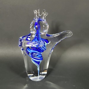 Könnte beinhalten: Eine klare Glasskulptur mit einem blau-weißen Wirbeldesign. Das Kunstglasstück hat eine kronenartige Oberseite und einen ausgestreckten Arm. Das Innere zeigt eine lebendige blaue Spirale, die einen auffälligen visuellen Effekt erzeugt. Die Skulptur ist ein dekoratives Kunstwerk.