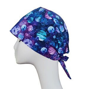 May include: A purple and blue patterned surgical scrub hat with a tie. The pattern features watercolor-style planets and flowers.