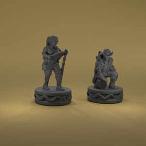 May include: Two gray painted miniature figurines of fantasy characters. The first is a female figure with a staff and a book, standing on a round base with a snake design. The second is a male figure with a backpack and a hat, kneeling on a round base with a snake design.