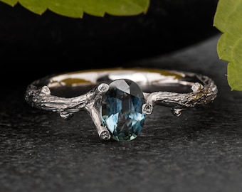 May include: A silver ring with a blue oval gemstone set in a branch-like design.