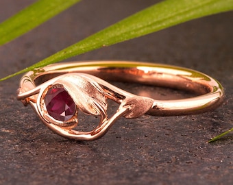 May include: A rose gold ring with a delicate leaf design and a single ruby gemstone.
