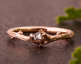 May include: A rose gold ring featuring a rough, grey diamond set in a branch-like band.