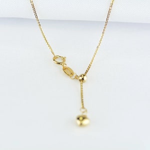 May include: A gold chain necklace with a sliding clasp and two small gold beads. The chain is delicate and has a fine, box-like link pattern.