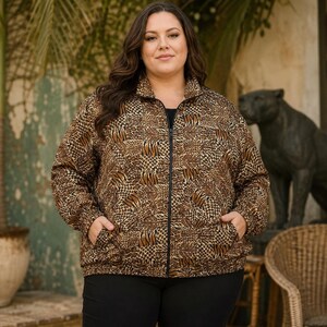 May include: A long-sleeve zip-up jacket featuring a brown and black animal print pattern with a mix of leopard and tiger stripes. The jacket has a high collar, a black front zipper, and two side pockets, worn over a solid black shirt and black pants.