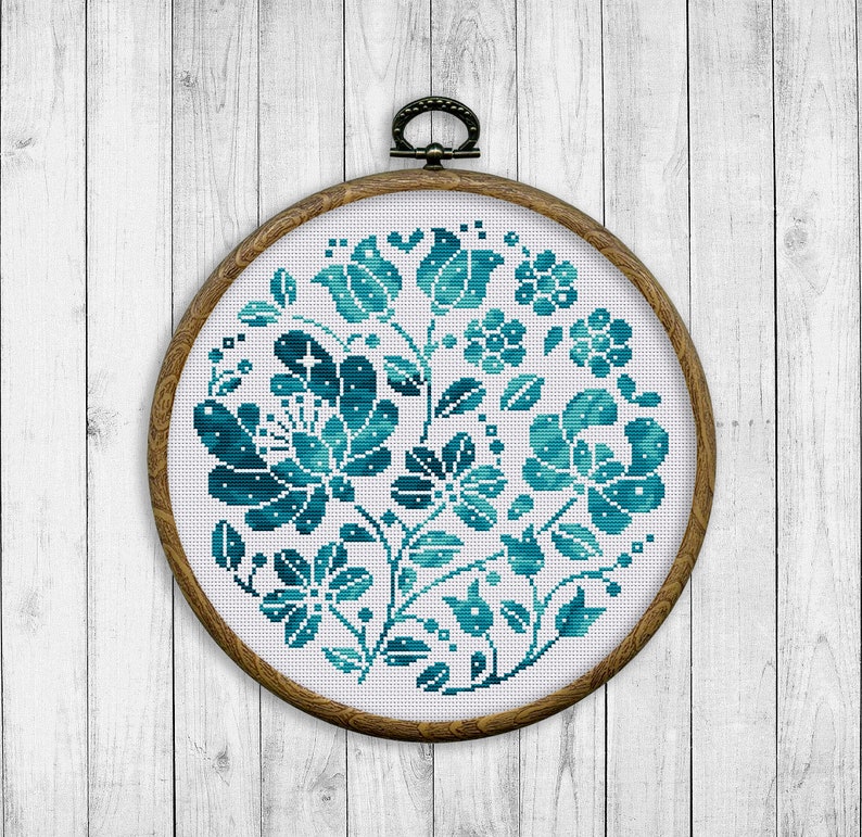 May include: A teal blue floral embroidery pattern in a round wooden embroidery hoop.