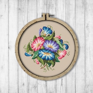 May include: A cross-stitch embroidery hoop with a floral design featuring pink, blue, and purple flowers with green leaves.