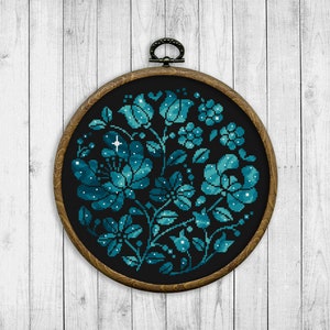 May include: A round embroidery hoop with a dark blue floral design on black fabric. The flowers are filled with white dots, resembling stars.