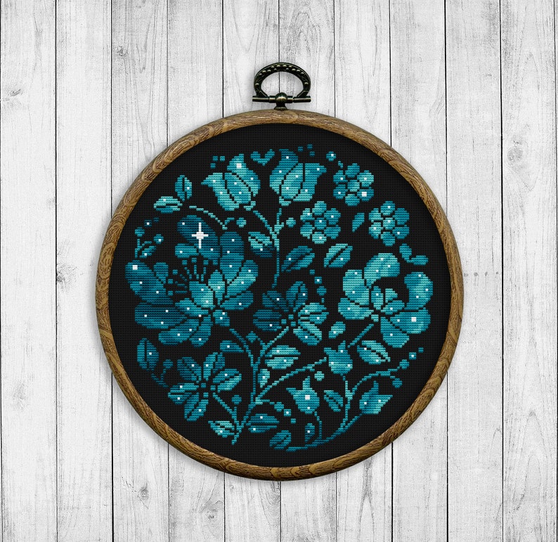 May include: A round embroidery hoop with a dark blue floral design on black fabric. The flowers are filled with white dots, resembling stars.