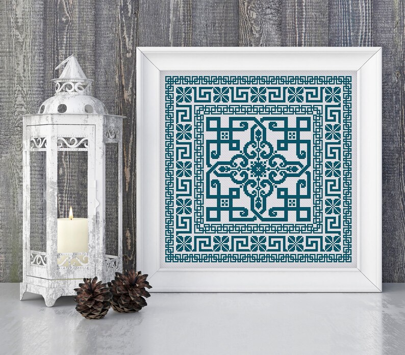 May include: A framed cross-stitch pattern with a teal blue geometric design. The design features a central square with a repeating pattern of interlocking shapes. The square is surrounded by a border of smaller squares and a repeating pattern of Greek key designs.