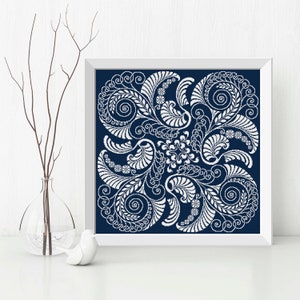 Op de afbeelding: Een ingelijst afdruk met een wit bloemenontwerp op een donkerblauwe achtergrond. Het ontwerp bevat ingewikkelde swirls en bladeren.