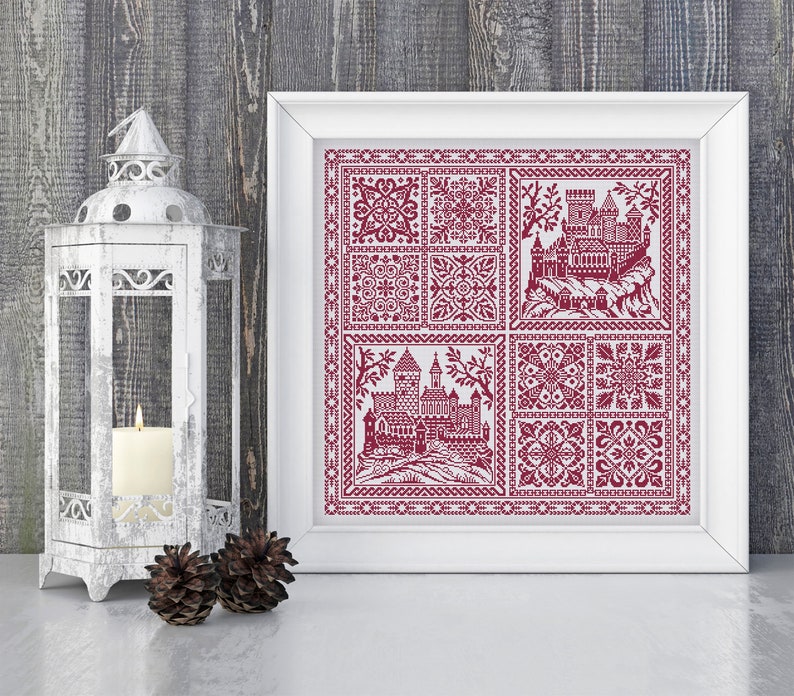 May include: A framed cross-stitch design featuring a red castle with a white background. The castle is surrounded by a border of red and white geometric patterns.