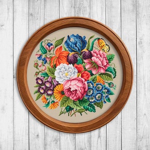 May include: A framed cross-stitch embroidery featuring a colorful bouquet of flowers, including roses, tulips, and other blooms. A butterfly is perched on a flower.