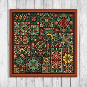 Op de afbeelding: Een kleurrijk kruissteekpatroon met verschillende geometrische vormen en bloemmotieven in tinten groen, rood, geel en oranje. Het patroon is ingelijst in een donkerbruin frame.