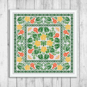 May include: A framed cross-stitch design featuring a symmetrical pattern of green leaves, orange gourds, yellow flowers, and a central butterfly. The design is bordered by a green geometric pattern and set against a white background.