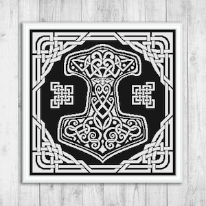 Può includere: Schema di punto croce in bianco e nero di un martello Mjolnir stilizzato con intricati disegni di nodi. Il martello è circondato da una cornice quadrata con nodi celtici.