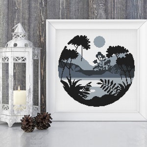 May include: Black and white cross stitch pattern of a circular landscape with trees, mountains, and a lake. The design is framed in a white frame.