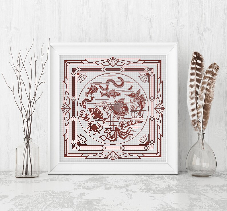 May include: A framed cross-stitch design featuring a red and white geometric pattern with a circle in the center. The circle contains a variety of sea creatures, including fish, a crab, an octopus, and a seahorse.