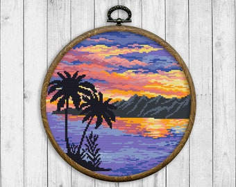May include: A framed cross-stitch embroidery depicting a sunset over a body of water with two palm trees in the foreground. The sky is a vibrant mix of orange, yellow, and purple hues.