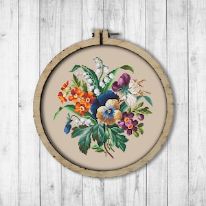 Może przedstawiać: Obręcz do haftu krzyżykowego z kwiatowym wzorem. Wzór przedstawia bukiet żółtych, pomarańczowych, fioletowych, niebieskich i białych kwiatów z zielonymi liśćmi.