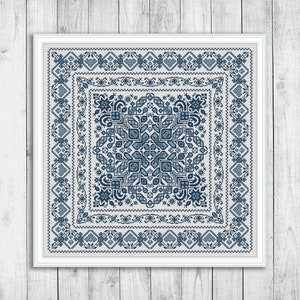 Può includere: Un ricamo a punto croce incorniciato con un design geometrico blu e bianco. Il design presenta un quadrato centrale con un motivo ripetitivo di stelle e diamanti.