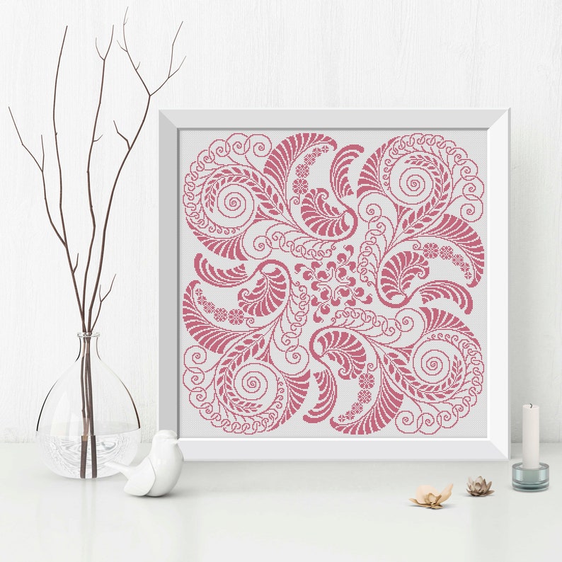 Op de afbeelding: Een roze en wit bloemenontwerp met ingewikkelde swirls en bladeren. Het ontwerp is ingelijst in een wit frame.