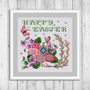 May include: Cross-stitch pattern featuring a colorful Easter egg design with the text "HAPPY EASTER". The design includes pink butterflies, green leaves, and purple flowers.