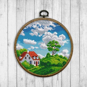 Pode incluir: Um bordado de ponto cruz enquadrado que retrata uma casa branca com telhado vermelho, árvores verdes e um céu azul com nuvens brancas.