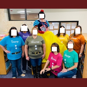 May include: A group of teachers dressed as Snow White and the Seven Dwarfs for a school event. The teachers are wearing colorful t-shirts with the names of the dwarfs printed on them. Snow White is wearing a white dress with a red bow and holding a book that says "Snow White".
