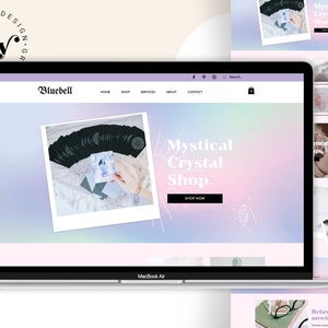 May include: A laptop computer displaying a website for a mystical crystal shop. The website features a pink and blue gradient background with a white text overlay that reads "Mystical Crystal Shop." The website also features a photo of a hand holding a deck of tarot cards.