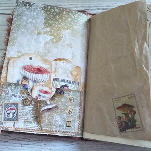 K&ouml;nnte beinhalten: Offenes Journal mit dekorierten Seiten. Es zeigt Pilz-Themen-Tags, Vintage-Ephemera und eine Briefmarke mit Pilz-Illustrationen. Das Journal hat eine rustikale, handgemachte &Auml;sthetik mit einer gen&auml;hten Bindung.