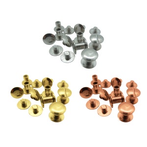 Könnte beinhalten: Sortiment aus Metallnieten in drei Farben: Silber, Gold und Kupfer. Die Nieten befinden sich in verschiedenen Montagephasen, einige haben das obere Teil befestigt und andere das untere Teil befestigt.