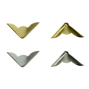 Könnte beinhalten: Vier Eckenschutz, zwei golden und zwei silberfarben, in Form eines V mit abgerundeter Spitze.