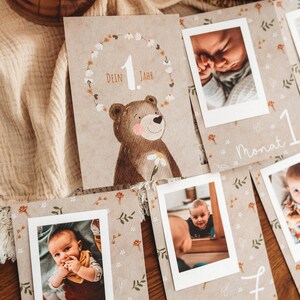 Pu&ograve; includere: Un set di biglietti per tappe fondamentali del bambino con foto. Le carte presentano un'illustrazione di orso e le parole "1 Jahr" e "Monat". Le carte sono decorate con motivi floreali e di foglie e includono foto di un bambino.