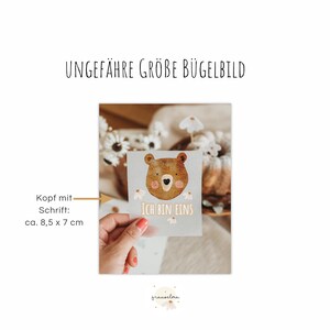 Peut inclure: Une petite carte bleu clair avec une illustration &agrave; l'aquarelle d'une t&ecirc;te d'ours et le texte "ICH BIN EINS". La carte mesure environ 8,5 x 7 cm. L'image comprend &eacute;galement le texte "UNGEF&Auml;HRE GR&Ouml;BE B&Uuml;GELBILD".