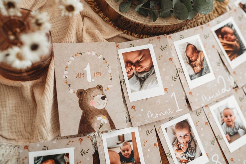 Pu&ograve; includere: Una collezione di biglietti per bambini con foto, con un'illustrazione di orso e la scritta "Dein Jahr". Le carte sono disposte con foto di un bambino, con numeri e la parola "Monat" su alcune carte.