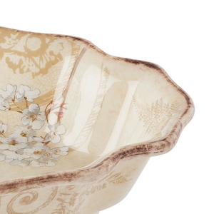 May include: A white ceramic bowl with a scalloped rim and a floral design. The bowl has a distressed look and is decorated with brown and grey accents.