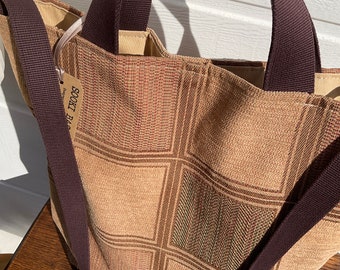 May include: A brown and tan checkered tote bag with a dark brown strap and handles. The bag has a small tag that says "SOOKET BAG".