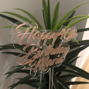 May include: Clear acrylic cake topper with the text "Happy 40th Birthday Mario" in rose gold lettering.