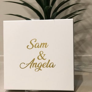 May include: White gift box with the names Sam & Angela written in gold lettering.